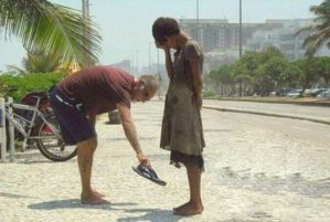 A-man-giving-a-homeless-woman-his-shoes